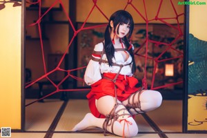 A woman in a red and white dress tied up with a rope.