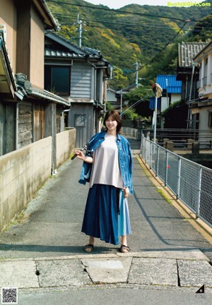 A woman standing in the middle of a street next to a bus.