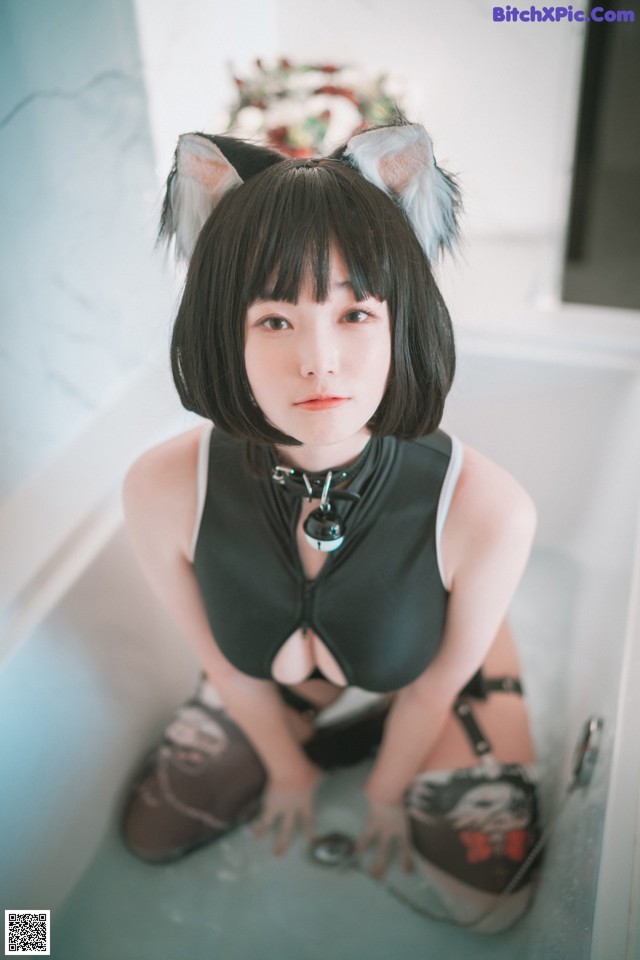 A woman sitting in a bathtub wearing a cat ears headband.