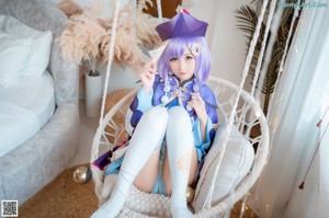 A woman in a blue and purple outfit sitting on a swing.