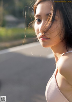 A woman with long brown hair standing in a field.