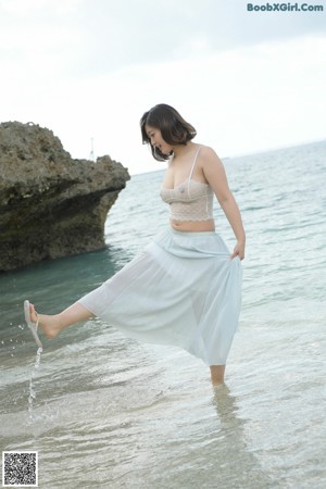 A woman in a white bikini standing on a beach.