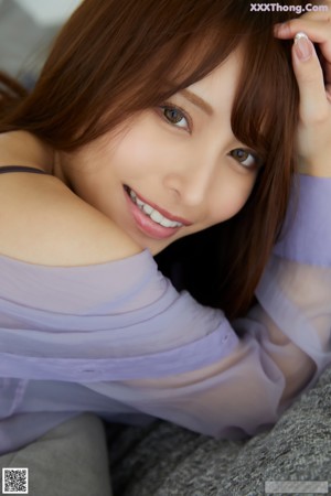 A woman in a purple shirt is standing in the shower.