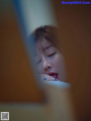 A woman laying on top of a bed next to a pillow.