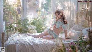 A woman sitting on a bed surrounded by flowers.