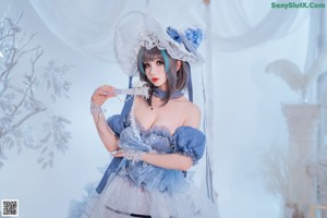 A woman in a blue and white lingerie sitting on a bed.