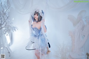 A woman in a blue dress and hat sitting on a bed.