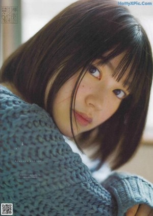 A young woman wearing a blue cardigan and a red shirt.