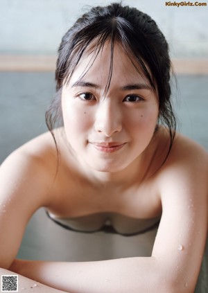 A woman in a bikini standing next to a swimming pool.