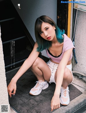 A woman with blue hair is sitting on a couch.