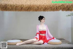 A woman in a red dress sitting on a wooden bench.