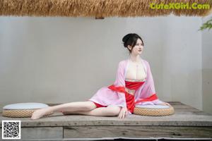 A woman in a red dress sitting on a wooden floor.