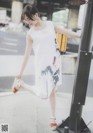 A woman in a red top and white skirt holding an umbrella.