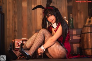 A woman in a bunny costume sitting at a table with bottles of alcohol.