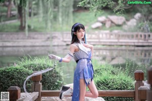 A woman in a blue and white outfit sitting on a ledge.