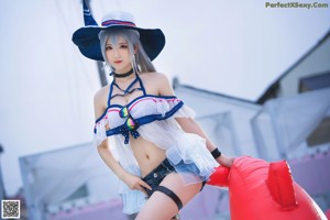 A woman in a sailor outfit sitting on a lounge chair by a pool.