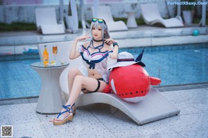 A woman sitting on a lounge chair next to a pool.