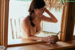 A woman in a beige bathing suit leaning against a wall.