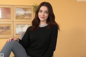 A woman sitting on top of a black couch.