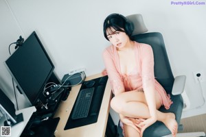 A woman in a pink lingerie sitting on a bed.