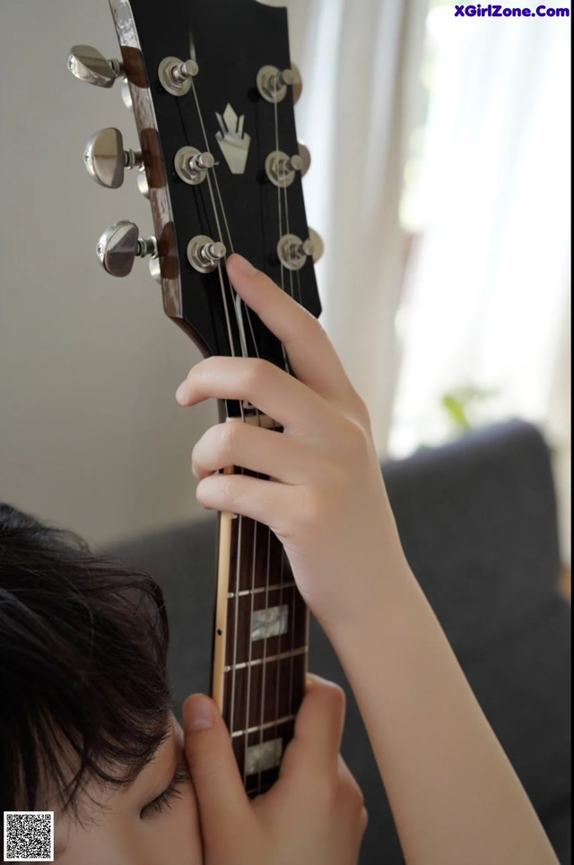 A person playing a guitar with their hands on the neck.