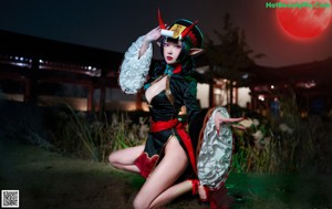 A woman in a black and red outfit holding a bunch of sticks.