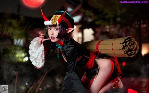 A woman in a black and red outfit sitting on a rock.