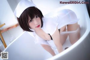 A woman in a white nurse outfit sitting on a chair.