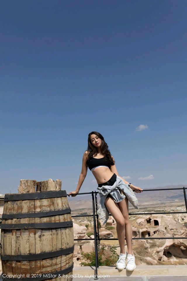 A woman standing on top of a wooden barrel.