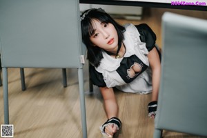 A woman in a maid outfit standing in a kitchen.