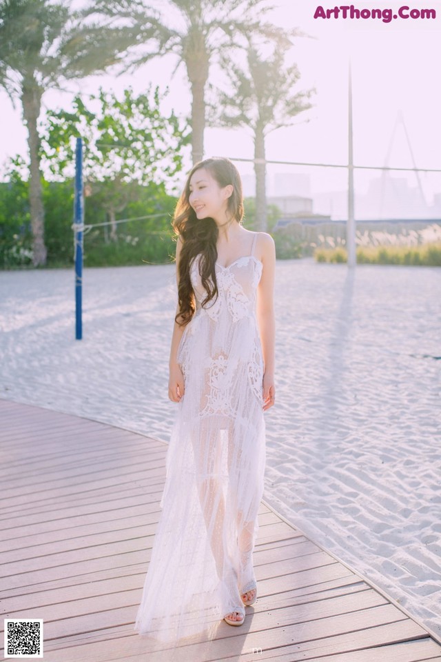 A woman in a white dress standing on a boardwalk.