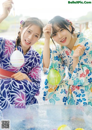 A couple of young women laying on top of a bed.