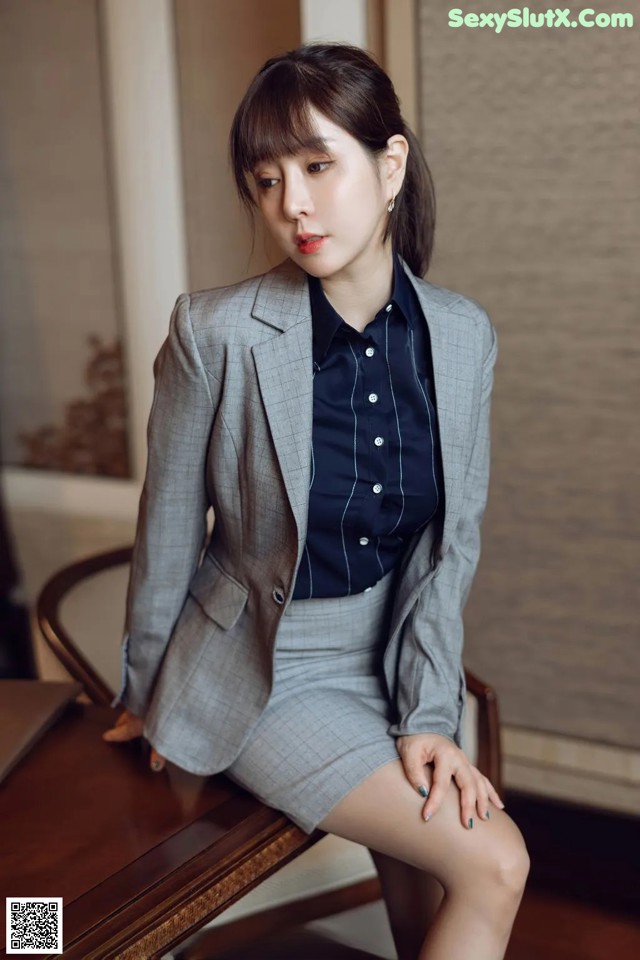 A woman in a gray suit sitting at a table.