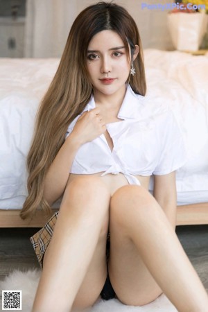 A woman sitting on the floor holding a book.