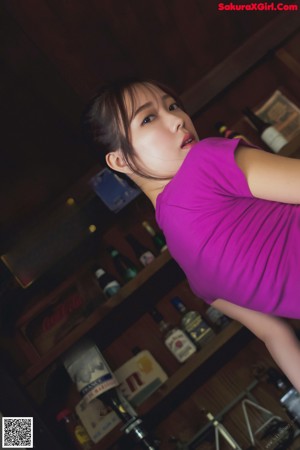 A woman in a pink bikini sitting at a bar.