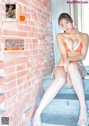 A woman in a blue bikini posing in front of a tree.