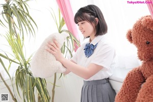 A woman in a school uniform sitting on a bed.