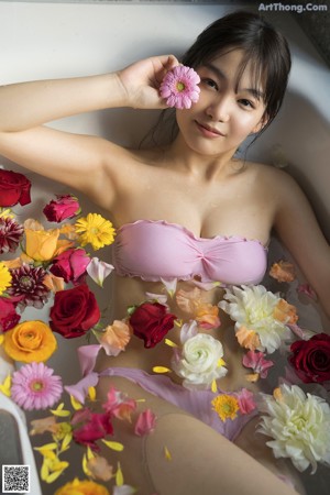 A woman in a pink bikini laying in a bathtub.