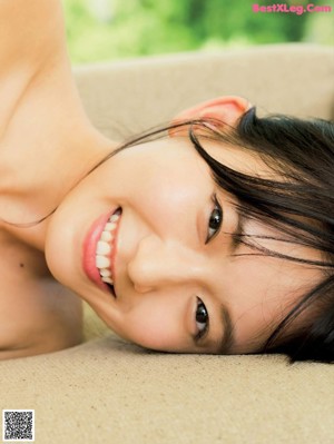 A woman in a white bikini sitting on a yoga mat.